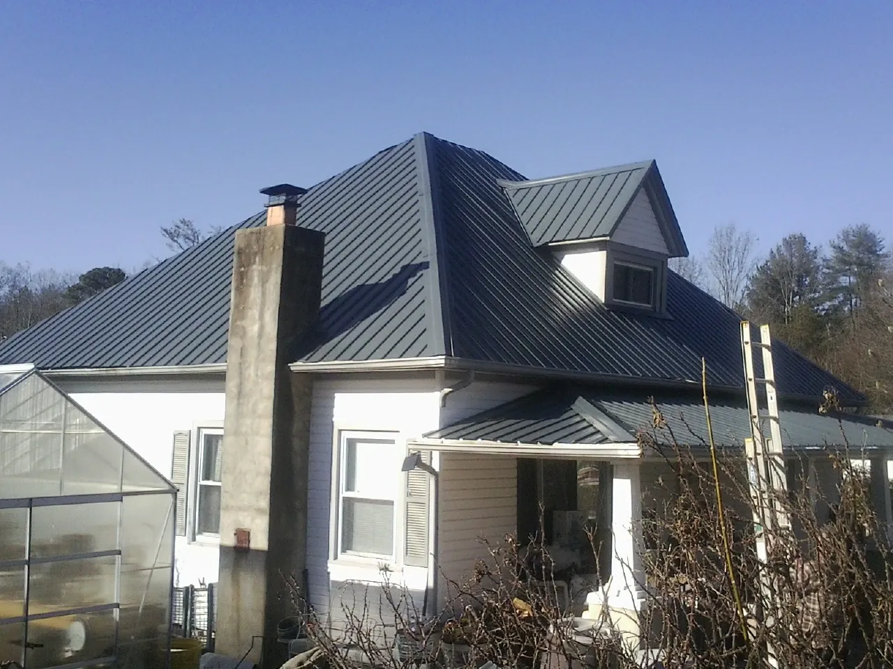 Dark blue standing seam metal roof on a white farmhouse with dormer — Slate & Tile Roof Repair by Roofing Brothers in Ashfield