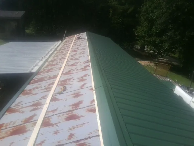 Old rusted panels beside newly installed green metal roofing — Wind Damage Roof Repair by Roofing Brothers in Ashfield