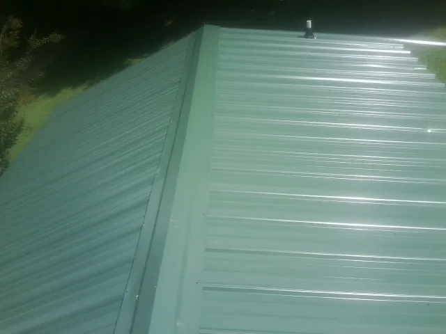 New green metal panels meeting at the ridge of a roof — Flat Roof Repair work by our crew in Ashfield