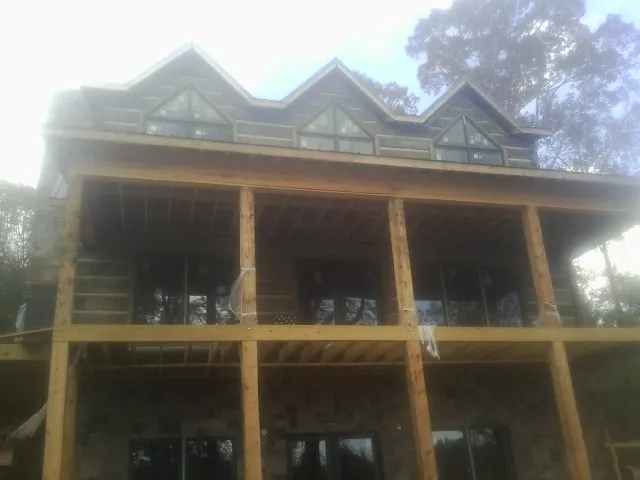 Dormers and porch framing on a large log home under construction — Roof Coating work by our crew in Ashfield