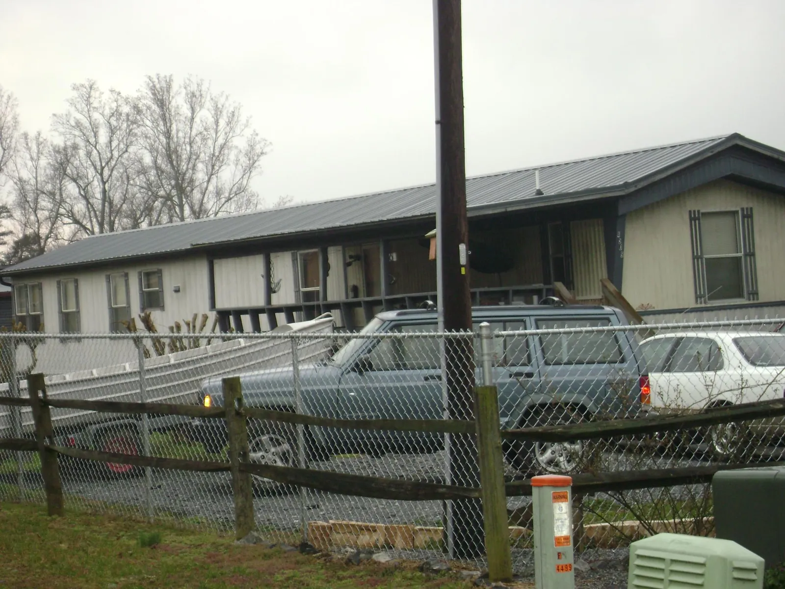 Dark metal roof on a long single story building behind a chain link fence in Ashfield