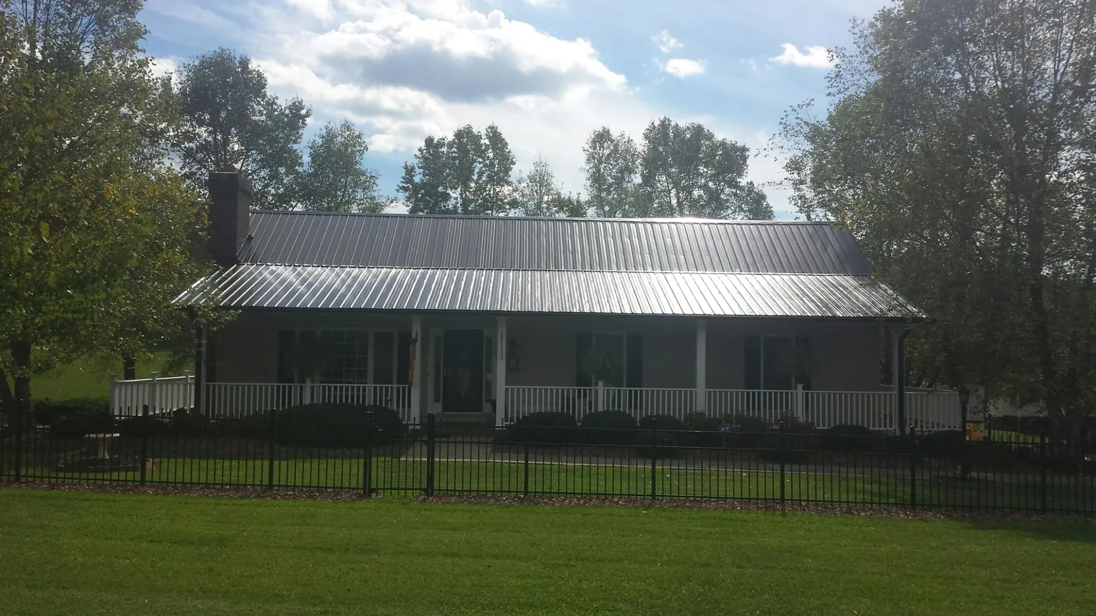 Gray metal roof on a brick ranch with a full width front porch — Gutter Guard Installation work by our crew in Ashfield