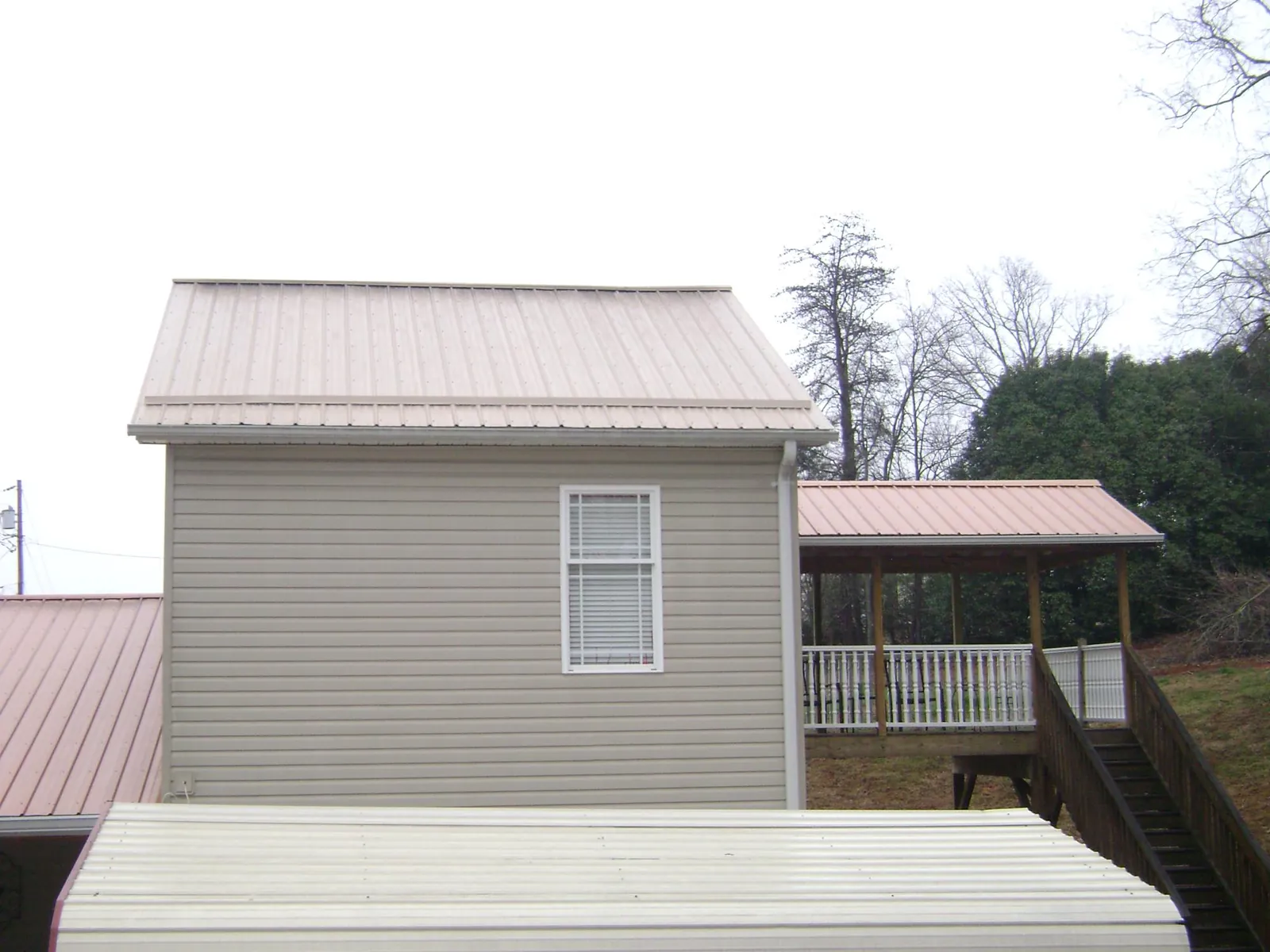 Tan metal roofs on a two story addition and attached porch, from a Roof Replacement job in Ashfield
